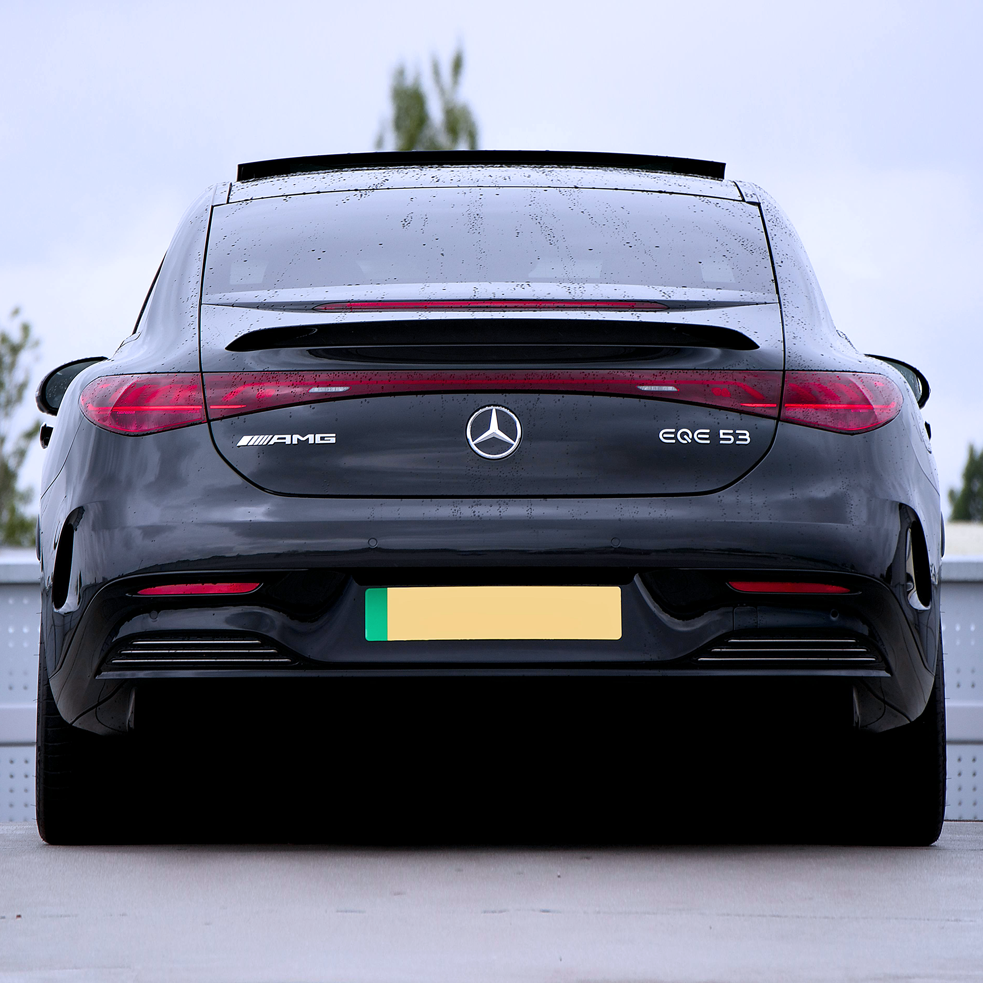 Rear view of an all-electric performance vehicle, shown outdoors in wet conditions