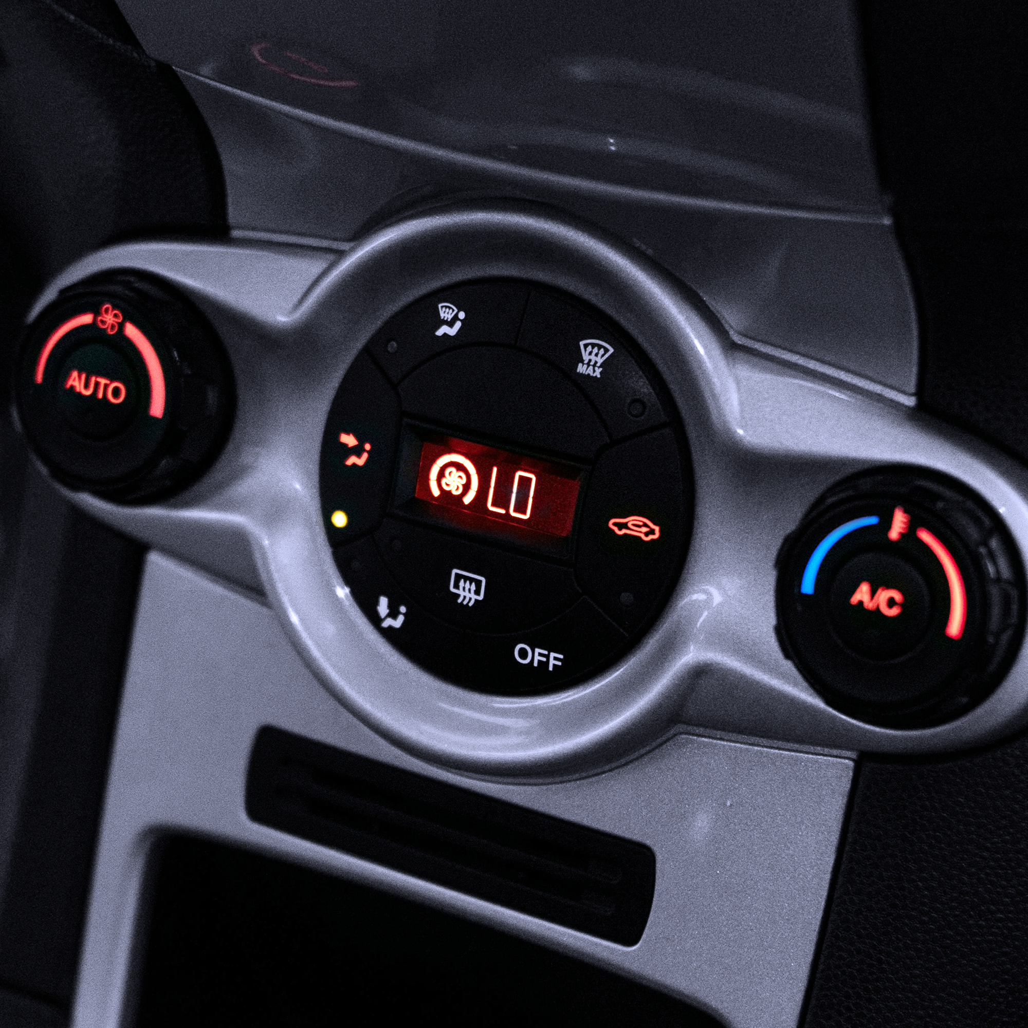 Close-up of a vehicle air conditioning control panel, highlighting climate control settings used during AC servicing